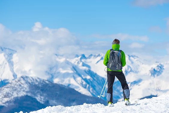 A cross country skier looks at the snowy view after climbing a summit
