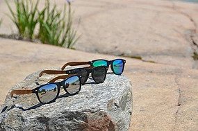 3 pairs of sunglasses are resting on a rock in the desert