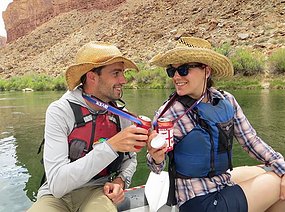 Two people cheer beers while floating on the Snake River