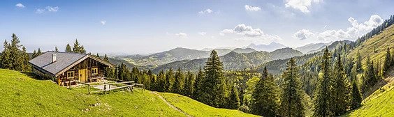 A panoramic shot of a log cabin in the hills outside of Jackson Hole