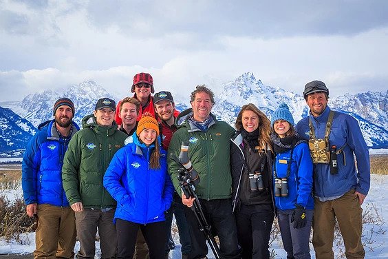 A group poses in front of the snowy Grand Tetons during the winter